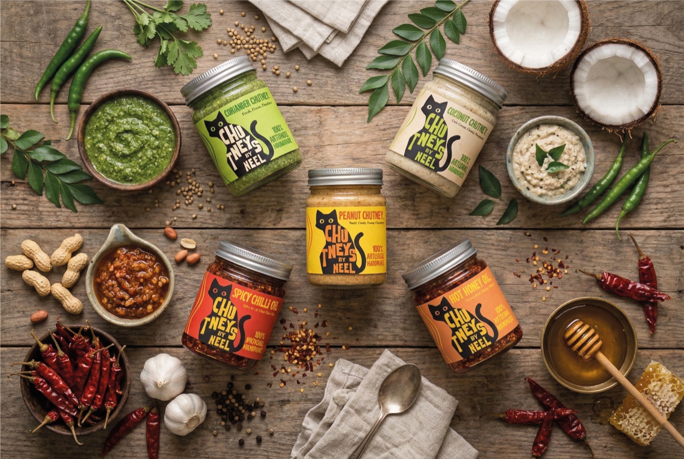 Chutneys By Neel jars on a wooden table with coconut, chillies, peanuts and honey